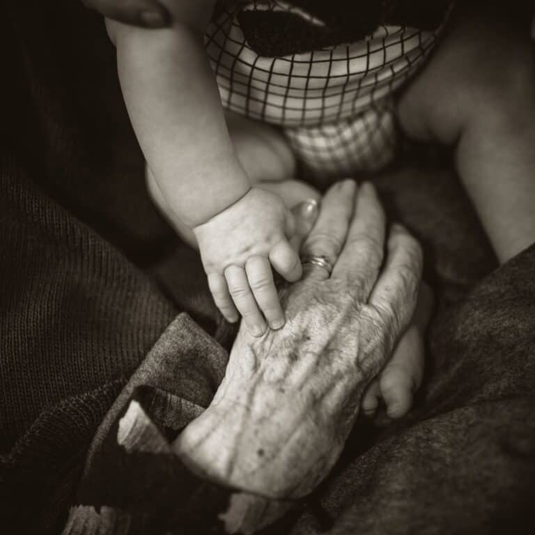 elderly hands touching baby hand