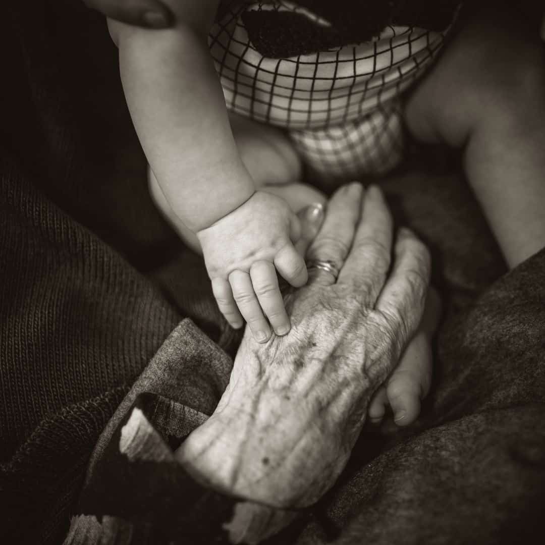 elderly hands touching baby hand