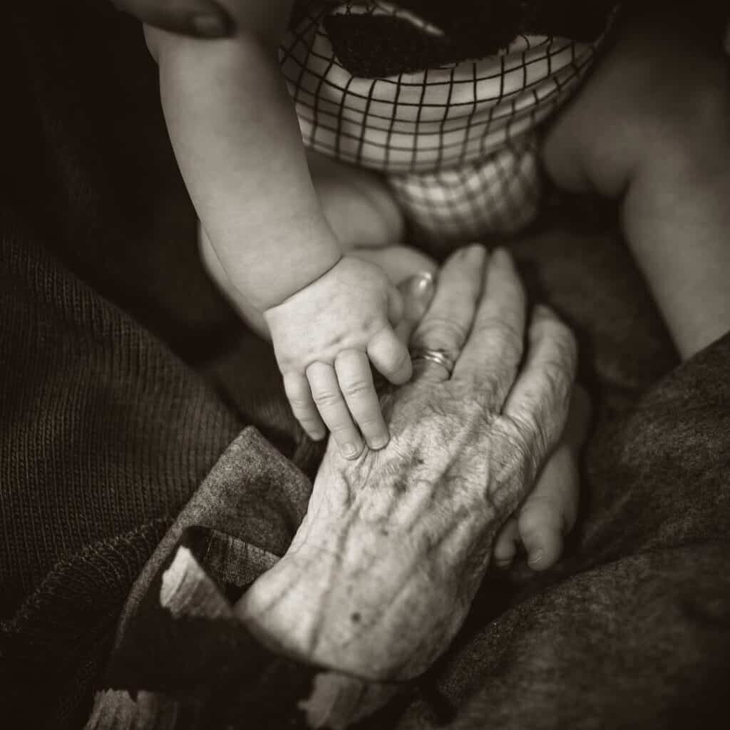 Bookends of Life elderly hands touching baby hand